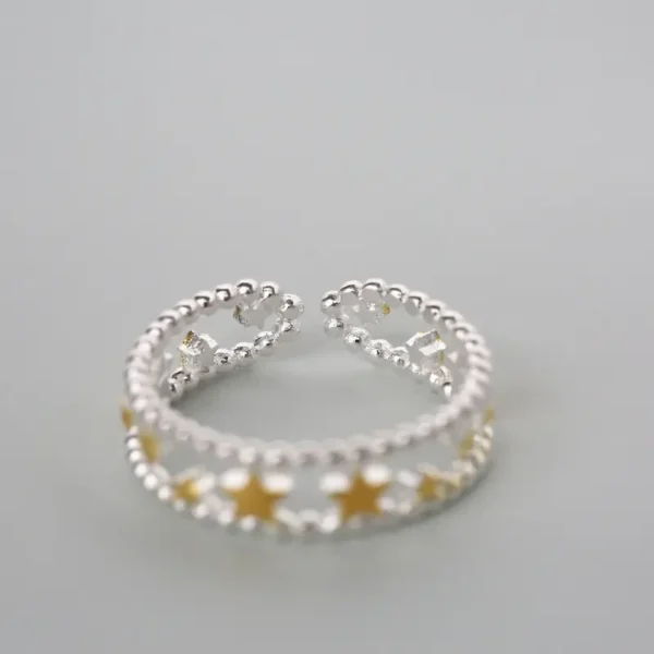 Sterling silver open ring with gold-plated stars arranged along a beaded band.