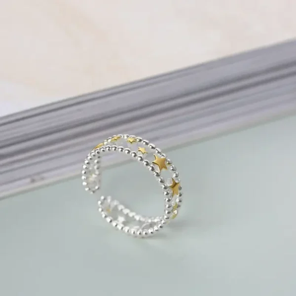 Sterling silver open ring with gold-plated stars arranged along a beaded band.