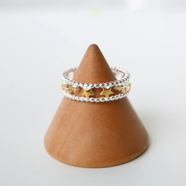 Sterling silver open ring with gold-plated stars arranged along a beaded band.