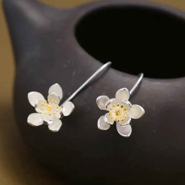 Sterling silver long flower earrings with gold accents.