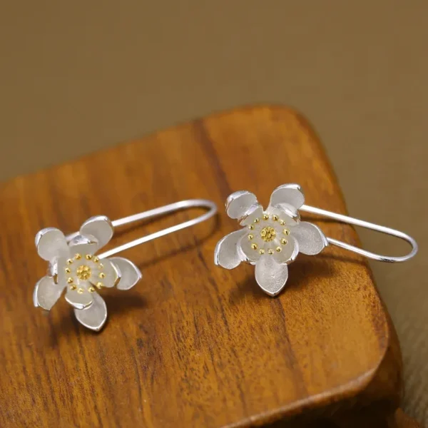 Sterling silver long flower earrings with gold accents.